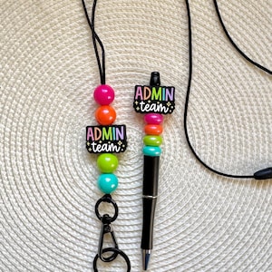 May include: A black lanyard with a black retractable pen and colorful beaded charms. The charms spell out "Admin Team" in rainbow colors.