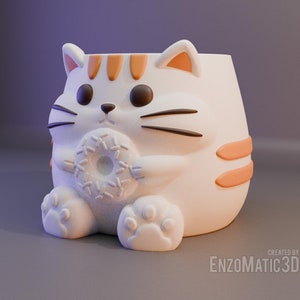 May include: White ceramic cat planter with orange stripes and a donut in its paws. The planter has a cute cartoon face with black eyes and whiskers.