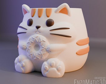 May include: White ceramic cat planter with orange stripes and a donut in its paws. The planter has a cute cartoon face with black eyes and whiskers.