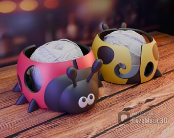May include: Two ladybug-shaped yarn bowls. One is red and black, the other is yellow and black. Each bowl holds a ball of white yarn. The bowls have antennae and leg-like protrusions, sitting on a wooden surface.