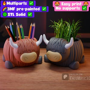 Op de afbeelding: Twee Highland-koe-vormige plantenbakken, één terracotta en één grijs, staan ​​naast elkaar op een houten oppervlak. De terracotta koe bevat kleurpotloden, terwijl de grijze koe groen gras bevat. Beide hebben witte hoorns en beige gezichten. De afbeelding bevat tekst die 3D-printfuncties aangeeft.