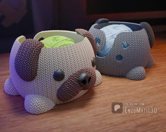 May include: Two knitted yarn bowls shaped like pugs. One bowl is beige with a green yarn ball inside, and the other is gray with a blue yarn ball inside.
