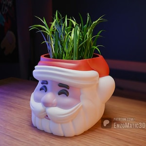 May include: A white Santa Claus planter with a red hat, holding a green plant. The planter has a smiling face with closed eyes and a white beard. The text "PATREON.COM/ENZOMATIC3D" is visible in the lower right corner of the image.
