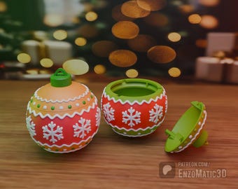Può includere: Un ornamento natalizio rosso e verde con un motivo a fiocco di neve bianco. L'ornamento è aperto e la metà superiore è separata dalla metà inferiore.