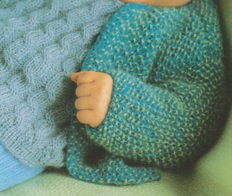 Puede incluir: Un jersey de punto azul para beb&eacute; con un patr&oacute;n texturizado. El jersey est&aacute; hecho con un hilo suave y tiene un corte holgado.