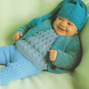 May include: A baby wearing a blue knitted hat with a long point, a blue knitted cardigan with a light blue knitted jumper underneath, and light blue knitted trousers.