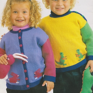 Könnte beinhalten: Zwei Kinder tragen bunte Strickpullover. Das Mädchen trägt eine blaue Strickjacke mit rosa Ärmeln und einem rosa Hasen auf der Vorderseite. Der Junge trägt einen gelben Pullover mit grünen Ärmeln und einem grünen Dinosaurier auf der Vorderseite. Beide Pullover haben blaue Borten.