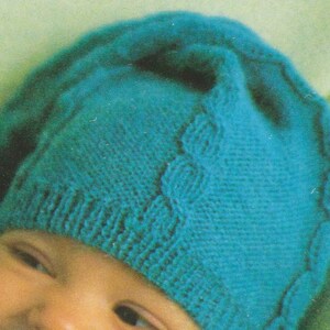 Puede incluir: Un gorro de beb&eacute; de punto azul turquesa con un patr&oacute;n de trenza.