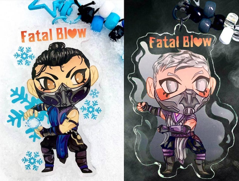 May include: Two clear acrylic charms featuring a cartoon character with a blue and purple outfit, a black mask, and a heart symbol. The text "Fatal Blow" is printed on both charms.