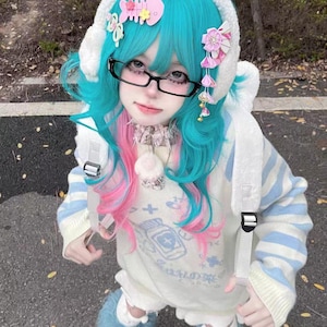 May include: A person wearing a blue and pink wig, black glasses, and a white sweater with blue stripes. The sweater has a graphic on the front. The person is also wearing a white hood with decorative accents and blue fuzzy boots.