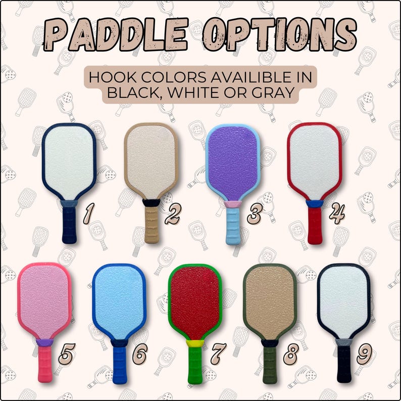 May include: Nine pickleball paddles with different color combinations. The text "PADDLE OPTIONS" is at the top. The text "HOOK COLORS AVAILABLE IN BLACK, WHITE OR GRAY" is below the title. Each paddle has a different colored handle and paddle face.
