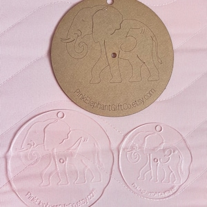 May include: Two round, clear acrylic ornaments with a silhouette of an elephant and a baby elephant. The ornaments have a hole at the top for hanging. The text "PinkElephantGiftCo.etsy.com" is printed on the bottom of each ornament.