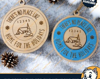 May include: Two versions of a wooden Christmas bauble with the text "There's no place like home for the holidays". The bauble is round and has a blue background with a white house and tree inside. The text is in a brown font. The bauble is hanging from a string.