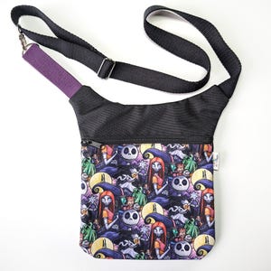Puede incluir: Bolso bandolera negro con un estampado colorido con personajes de Pesadilla antes de Navidad. El bolso tiene una correa negra ajustable, un acento morado y un bolsillo con cremallera. El bolso está hecho de una tela duradera.