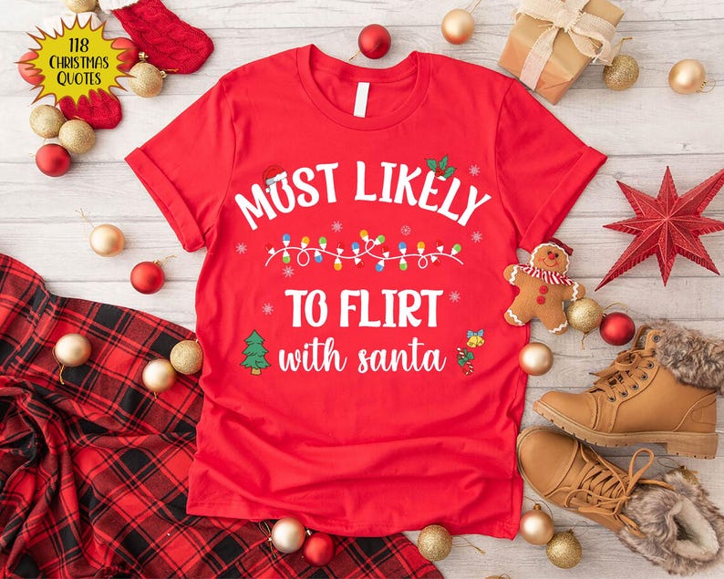 Może przedstawiać: Czerwona koszulka świąteczna z białym napisem "Most Likely To Flirt With Santa" i łańcuchem światełek choinkowych z zielonym drzewem i dzwonkiem po obu stronach napisu.