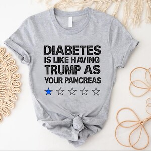 Puede incluir: Camiseta gris con el texto "La diabetes es como tener a Trump como p&aacute;ncreas" y una calificaci&oacute;n de una estrella.