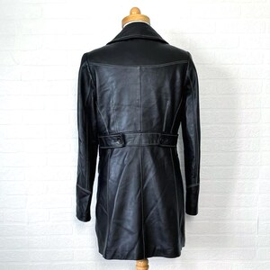 May include: Black leather coat with white stitching. The coat has a double breasted closure and a belt.