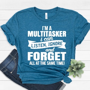 Puede incluir: Una camiseta azul turquesa con texto blanco que dice "Soy un multitarea, puedo escuchar, ignorar y olvidar todo al mismo tiempo!"