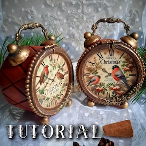 Puede incluir: Dos despertadores redondos de estilo vintage con marcos y asas de bronce metálico. Las esferas presentan ilustraciones de pájaros, acebo y piñas. Un reloj muestra el texto "Christmas is Here" y el otro "Merry Christmas".