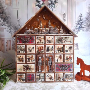 May include: A wooden house-shaped advent calendar with twenty-four numbered drawers. The top features a train and tree scene. Each drawer displays vintage-style illustrations of children, winter landscapes, and red plaid patterns with metallic accents.