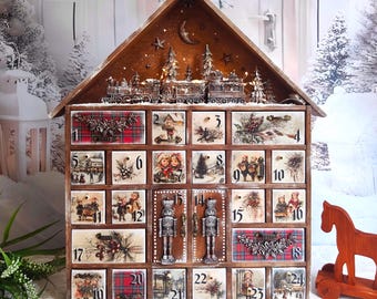 Puede incluir: Un calendario de adviento de madera con forma de casa y veinticuatro cajones numerados. La parte superior presenta una escena de tren y árboles. Cada cajón muestra ilustraciones de estilo vintage de niños, paisajes invernales y patrones de cuadros rojos.