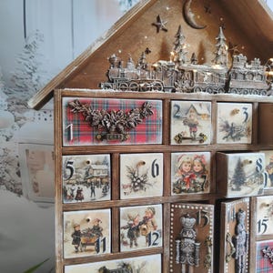 May include: A wooden advent calendar with numbered drawers featuring vintage holiday illustrations, including children, winter scenes, and a nutcracker. The top is decorated with a miniature train, pine trees, and a crescent moon.