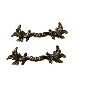 May include: Two ornate gold-toned metal drawer pulls with a leaf design.