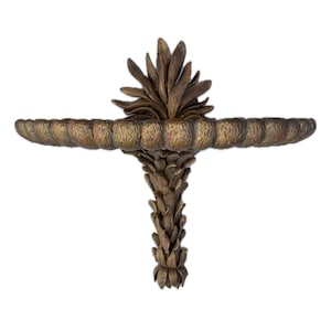 May include: A decorative wall shelf with a botanical design. The shelf is made of a bronze-colored material and features a palm frond-like support and a horizontal shelf with a textured edge. The shelf is approximately 18 inches wide.