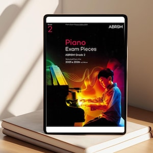 Può includere: Un tablet digitale che mostra la copertina di "Piano Exam Pieces ABRSM Grade 2", con un'illustrazione colorata di una persona che suona il pianoforte. Il tablet è appoggiato su una pila di libri bianchi. Il testo "Grade 2" e "ABRSM" è visibile.