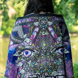 Puede incluir: Un pañuelo de tela negra con un estampado gráfico vibrante e intrincado en tonos morados, azules y verde neón. El diseño incluye patrones geométricos, ojos estilizados y el texto "ELEMENTS MUSIC AND ARTS FESTIVAL" en la parte inferior.