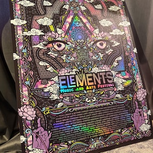May include: A rectangular poster for the Elements Music and Arts Festival featuring a central pair of eyes, intricate geometric patterns, and lotus flowers in shades of purple, pink, and blue. The text lists various musical artists and dates.