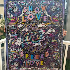 以下が含まれることがあります： カラフルな文字で「SHOW LOVE」と「SPREAD LOVE」と書かれた、鮮やかなサイケデリックアートプリント。渦巻く模様、漫画の雲、タイダイスタイルの「GRiZ」という名前が特徴で、装飾的なボーダーで縁取られています。