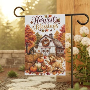 Puede incluir: Una bandera de jardín rectangular con el texto Harvest Blessings en letra cursiva marrón. La ilustración muestra un granero blanco, un gato atigrado sobre balas de heno, un cachorro dorado y calabazas naranjas entre hojas de otoño.