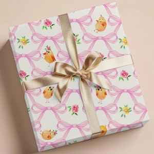 May include: White gift wrap with a repeating pattern of pink bows and yellow chicks. The gift wrap is tied with a gold ribbon.