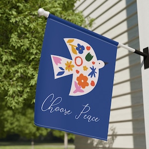 Puede incluir: Una bandera de jardín azul con una paloma blanca adornada con flores de colores y el texto "Choose Peace".