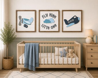 Könnte beinhalten: Ein Set aus drei quadratischen Wandbildern mit Holzrahmen, bestehend aus einem hellblauen Flugzeug, dem Text "FLY HIGH LITTLE ONE" mit blauen Wolken und einem dunkelblauen Flugzeug auf einem weißen Hintergrund mit horizontalen Linien.