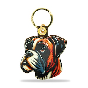 May include: A brown leather keychain with a gold key ring. The keychain features a colorful illustration of a boxer dog's head.