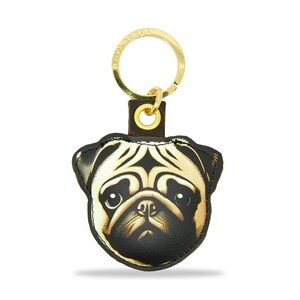 Könnte beinhalten: Ein goldener Schlüsselanhänger mit einem schwarzen Leder-Mops-Anhänger. Das Gesicht des Mopses ist in Schwarzweiß mit goldener Umrandung gedruckt.