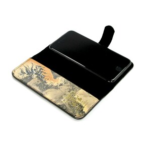 K&ouml;nnte beinhalten: Eine schwarze Leder-Handyh&uuml;lle mit Tiger-Druck. Die H&uuml;lle hat eine Klappe, die &uuml;ber das Telefon klappt, und einen Steckplatz f&uuml;r eine Kreditkarte.