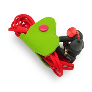 May include: Green leather cord keeper with a red button closure. Red and black Sony headphones are wrapped around the keeper.