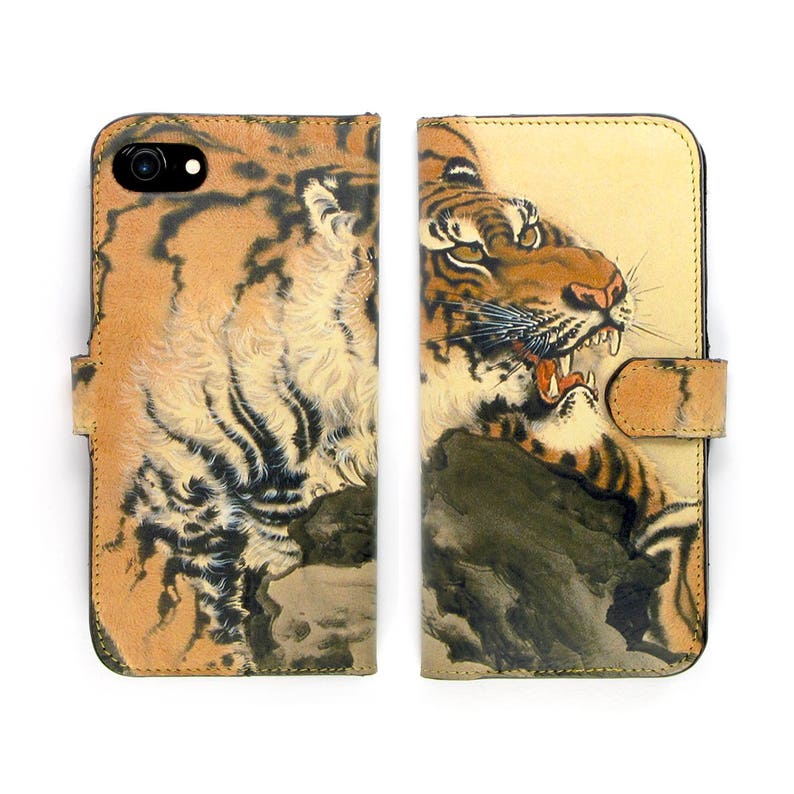 K&ouml;nnte beinhalten: Eine braune Leder-Handyh&uuml;lle mit einem Tiger-Design. Der Tiger ist in traditionellem japanischem Stil mit einem wilden Ausdruck dargestellt. Die H&uuml;lle hat eine Klappe, die den Bildschirm des Handys bedeckt.
