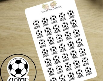 May include: A white sticker sheet featuring thirty-five small black and white soccer ball icons, each paired with the word GAME in black text. At the top, the text Twice As Nice Lettering appears with two cartoon character illustrations.