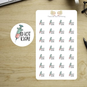 May include: A rectangular sticker sheet and a circular sticker featuring a syringe illustration filled with pink liquid and the black text SHOT DAY. The sheet includes twenty-eight identical syringe stickers and the text Twice As Nice Lettering.