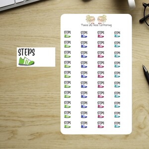 May include: A sheet of planner stickers with the word "STEPS" and a shoe graphic. The stickers are in green, blue, pink, and teal, with the text "STEPS" above each shoe. The top of the sheet has the text "Twice As Nice Lettering".