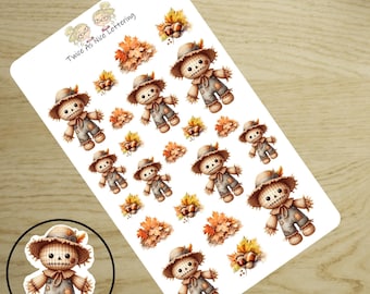 May include: A sticker sheet featuring multiple illustrations of scarecrows wearing straw hats and overalls, interspersed with autumn leaves and acorns. The text Twice As Nice Lettering is printed in the top left corner of the white sheet.
