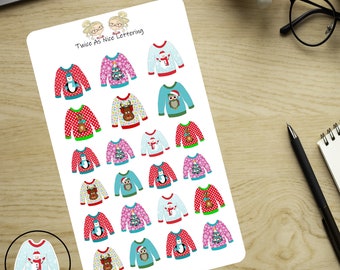 May include: A white sticker sheet featuring multiple small illustrations of holiday sweaters in red, pink, and blue. The sweaters display festive graphics including penguins, reindeer, owls, snowmen, and Christmas trees. The text Twice As Nice Lettering is printed at the top. A magnifying glass shows one snowman sweater.