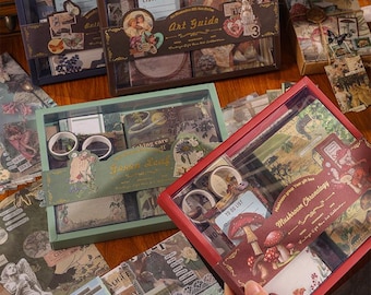May include: A collection of vintage-style stationery sets, including stickers, washi tape, and paper ephemera, presented in decorative boxes. The boxes are in shades of brown, red, and green. Some boxes feature text such as "Art Guide" and "Mushroom Chronology."