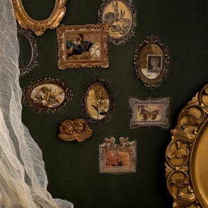 May include: A collection of vintage-style stickers featuring ornate gold frames and oval shapes. The stickers showcase images of cherubs, butterflies, and botanical illustrations, set against a dark green background.