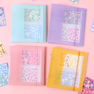 May include: Four pastel-coloured document folders in blue, purple, pink, and yellow. Each folder has a clear window and an elastic band closure. The folders contain patterned inserts with abstract designs, perfect for organizing papers.