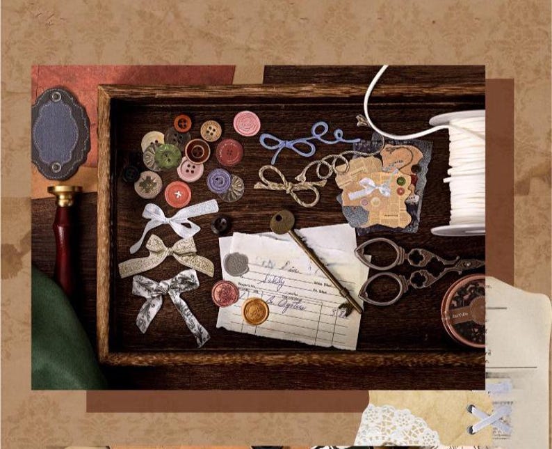 May include: A wooden tray filled with craft supplies, including colorful buttons, bows, scissors, a spool of white thread, and a vintage key. The arrangement includes a wax seal and a handwritten note, suggesting a theme of vintage crafting.